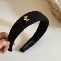 Détail d'un serre-tête noir en maille côtelée avec un charm de poney doré élégant - Style 5 Serre-tête Rayé Noir Cheval