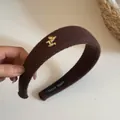 Détail d'un bandeau en tricot marron avec breloque cheval dorée et étiquette tissée. - Style 6 Serre-tête Rayé Café Cheval