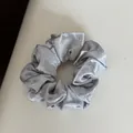 Detailed close-up of a silver satin hair scrunchie with white bow patterns for hair accessories. - Hair Tie / Blue