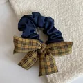 Detailed macro view of a navy blue fabric scrunchie with a mustard yellow plaid bow - Yellow-Black Striped Bow Blue Scrunchie