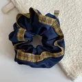 Detailed view of a blue denim scrunchie with a tan plaid border and Hand Made tag. - Yellow-Black Striped Blue Scrunchie