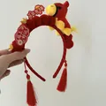 Vue détaillée d'un serre-tête rouge du Nouvel An chinois avec cheval en peluche et glands. - Serre-tête Pompon en Peluche Rouge