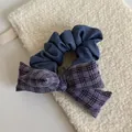 Close-up detail of a purple plaid bow scrunchie displayed on a cream textured pouch - Purple Striped Bow Blue Scrunchie