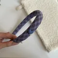 Close-up of a purple plaid fabric headband featuring a charming blue heart ornament detail - Purple Striped Headband with Blue Heart