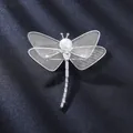 Detailed macro view of a silver dragonfly brooch with pearl and intricate mesh wings - Silver White