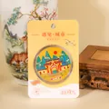 Detailed close-up of a Guilin landmark metal coin souvenir in its yellow packaging. - Guilin Commemorative Coin / Jingjiang Princes' Palace
