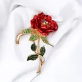 Close-up detail of a vintage red rose brooch with green enamel leaves and rhinestones - KC Gold Rose