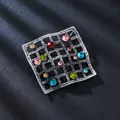 Vintage-Brosche aus Silber mit farbigen Strasssteinen auf dunklem strukturiertem Stoff - Quadratische Bunte Diamanten