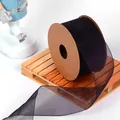 Close-up detail of black semi-transparent organza ribbon roll on decorative wooden pallet - 4CM Wide x 9.14 Meters Long / Mountain Black