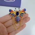 Close-up of a vintage bee brooch with colorful enamel wings and blue rhinestones. - KC Gold, Chain Bee