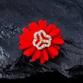 Detailed view of red daisy brooch featuring sparkling rhinestone center on dark rock - Daisy Style / Red