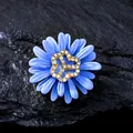 Detail of blue daisy brooch with crystal-encrusted gold-tone center on stone background - Daisy Style / Light Blue