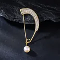 Detailed view of an elegant curved gold brooch featuring rhinestones and a hanging pearl - White