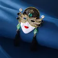 Macro shot of a vintage queen mask brooch with green crystals and black tassels - Antique Gold, Queen Mask Tassel