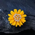 Macro detail of yellow daisy brooch with rhinestones on dark rock background - Daisy Style / Yellow
