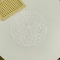 Dettaglio di tovaglietta in pizzo ricamato bianco con eleganti motivi floreali. - 27cm / Bianco