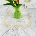 Close-up detail of cream embroidered lace placemat with intricate floral cutout patterns. - 30cm Square / Beige