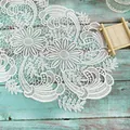 Close-up detail of white water-soluble lace floral placemat on teal wooden background - 25cm Round / Camel