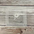 Macrodetail van een elegante kanten placemat met bloemenborduursel op houten tafel - Vierkante Centrum Bloem Stijl