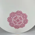 Detailed view of a pink circular embroidered lace coaster with intricate hollow floral patterns. - 28cm Round / Rouge Red