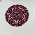 Detail view of intricate burgundy lace placemat with floral embroidery and cut-outs - 27x27cm / Burgundy