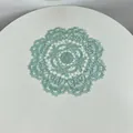 Detailed view of a mint green round embroidered lace placemat with floral pattern. - 28cm Round / Lake Green