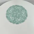 Detailed overhead view of a mint green embroidered lace placemat on a white table. - 27x27cm / Lake Green