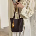 Vintage dunkelbraune gewebte Leder-Eimertasche, getragen von einem Modell im Cremekleid - Mit Anhänger / Kaffeebraun