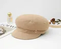 Detailed side view of a brown wool newsboy hat featuring a small gold logo accent - Khaki