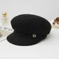 Classic black wool newsboy hat featuring a small gold metallic logo detail. - Black