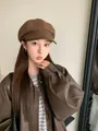 Vintage brown wool newsboy cap with leather brim detail worn by a model in soft light - Coffee