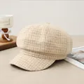 Dettaglio di un berretto vintage a quadri beige appoggiato su un tavolo di legno - Scozzese Beige Albicocca