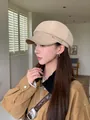 Elegant beige wool newsboy hat with leather brim, stylishly worn by model in profile - Beige