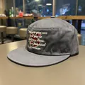 Detailed view of white cursive embroidery and red letter S on gray flat brim cap - Charcoal Grey