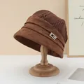 Detailed shot of a brown knit and suede bucket hat featuring a sparkly rhinestone buckle - Rhinestone Metal Buckle Style / Coffee