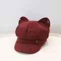 Detailed view of a burgundy cat ear octagonal hat featuring a silver metal G logo - Red