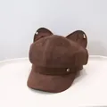 Detailed shot of a brown suede octagonal beret featuring cute cat ears and a metal G logo - Coffee