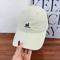 Detailed close-up of cream baseball cap featuring 'oi look at me' navy blue embroidery - Off White