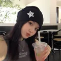Stylisches asiatisches Mädchen mit schwarzer Y2K-Punk-Mütze und silbernem Stern im Café - Schwarz