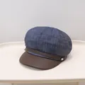 Detail of a denim newsboy cap with a brown leather brim and decorative side buttons - Denim Blue