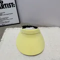 Minimalistischer gelber Sonnenhut mit verstellbarem Riemen auf strukturiertem Teppich - Gelb