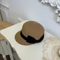 Elegant detail of a women's straw baseball hat decorated with a black ribbon bow - Khaki