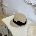 Detailed macro view of a summer straw equestrian hat featuring a stylish black bow ribbon - Beige