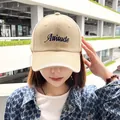 Close-up detail of beige baseball cap with navy blue Attitude embroidery on Asian model - 60-65 / Khaki