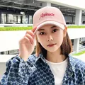 Close-up detail of a pink cotton baseball cap featuring Attitude embroidery worn by a model - Pink