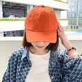 Close-up of a vibrant orange quick-dry baseball cap worn outdoors by a model for sun protection - Orange