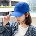 A close-up side view of a woman wearing a vibrant blue quick-dry baseball cap outdoors - Blue