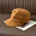 Close-up of pleated camel suede newsboy cap with soft texture on leather background - Khaki