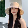 Close-up of an elegant pleated sun hat for women in beige worn by a female model - Khaki