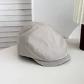 Gros plan d'une casquette gavroche grise à rayures rétro posée sur une table blanche. - Beige